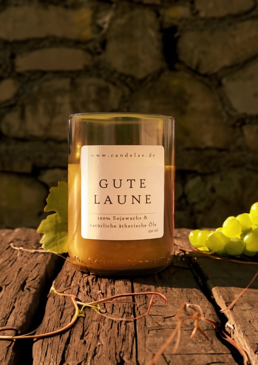 Duftkerze „Gute Laune“ aus Sojawachs im Glas aus recycelter Weinflasche, auf Holzuntergrund