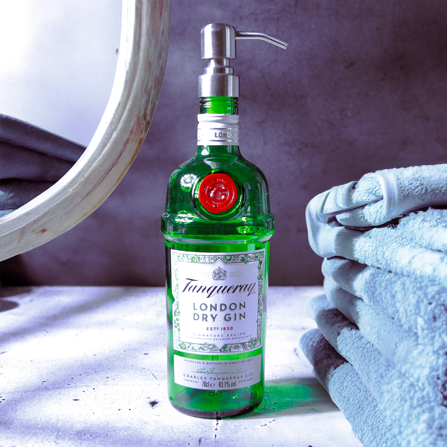 Nachhaltiger Seifenspender aus einer recycelten Tanqueray London Dry Ginflasche mit edler Metallpumpe, stilvoll arrangiert neben weichen Handtüchern – perfektes Upcycling-Accessoire für Bad und Küche