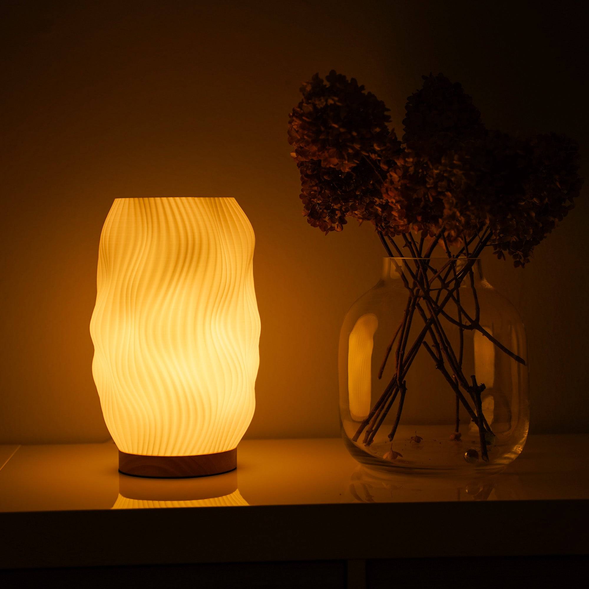 Moonou Flow 3D-gedruckte Tischlampe mit Wellenstruktur und Eichenholz-Sockel, warmes Licht auf dem Sideboard neben großer Glasvase