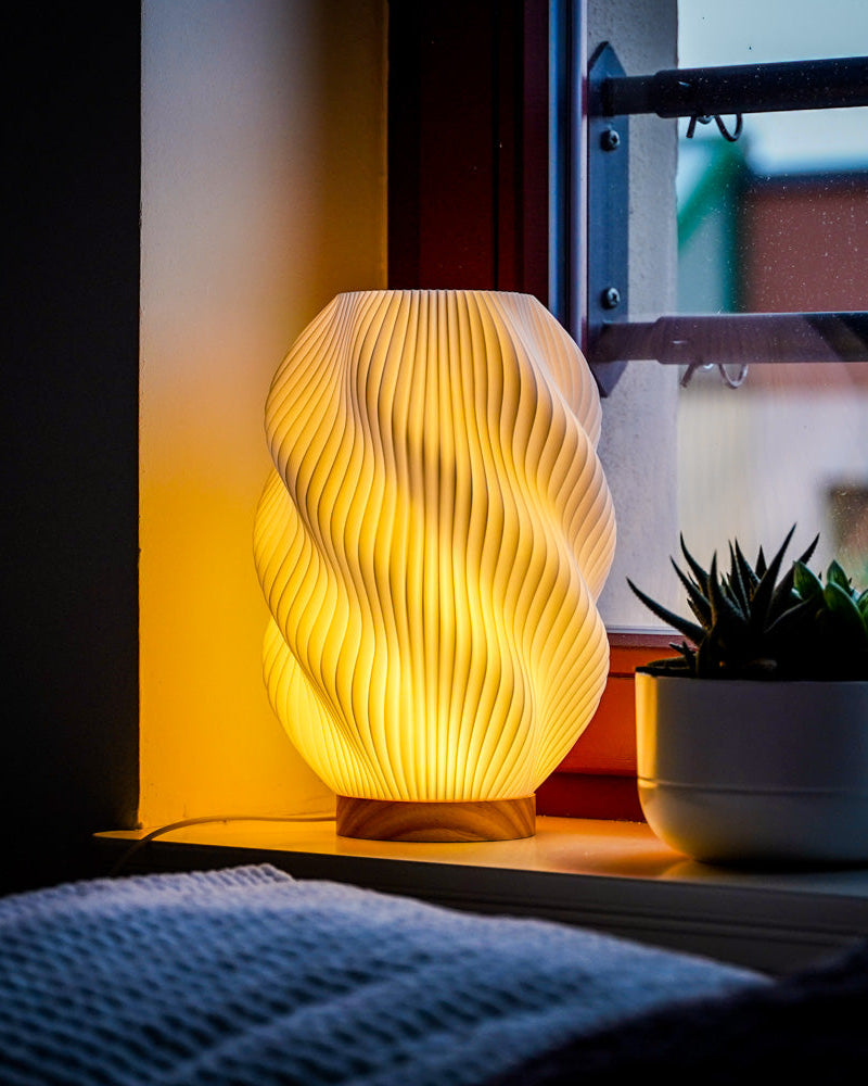 Moonou Twuro 3D-gedruckte Tischlampe aus PLA mit Spiralstruktur und Eichenholz-Sockel, warmes Licht auf der Fensterbank neben Sukkulente