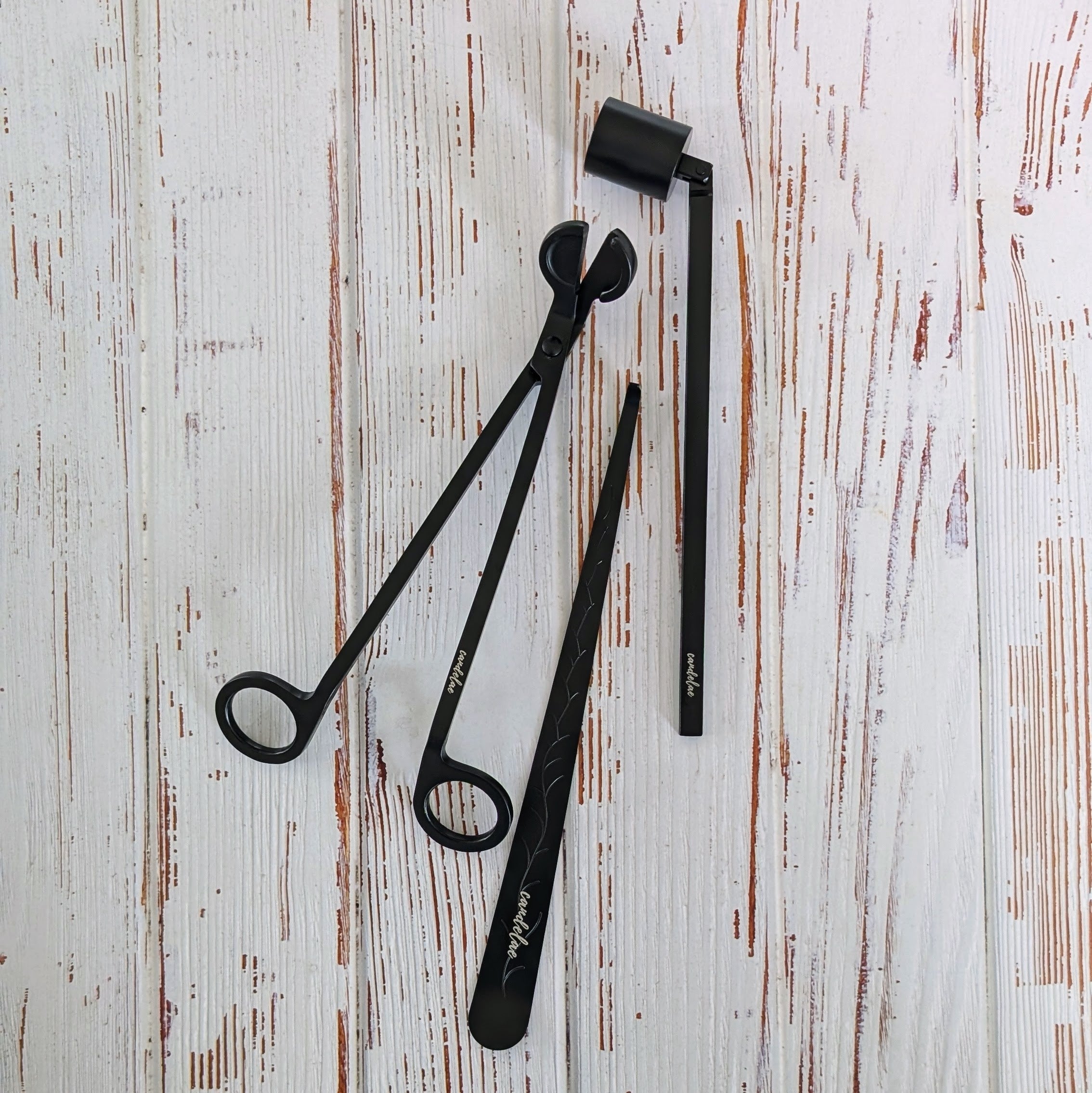 Kerzenpflege-Set in Schwarz – Dochtschere, Kerzenlöscher & Dochtheber aus Edelstahl auf hellem Holztisch, Candelae Zubehör für Duftkerzen
