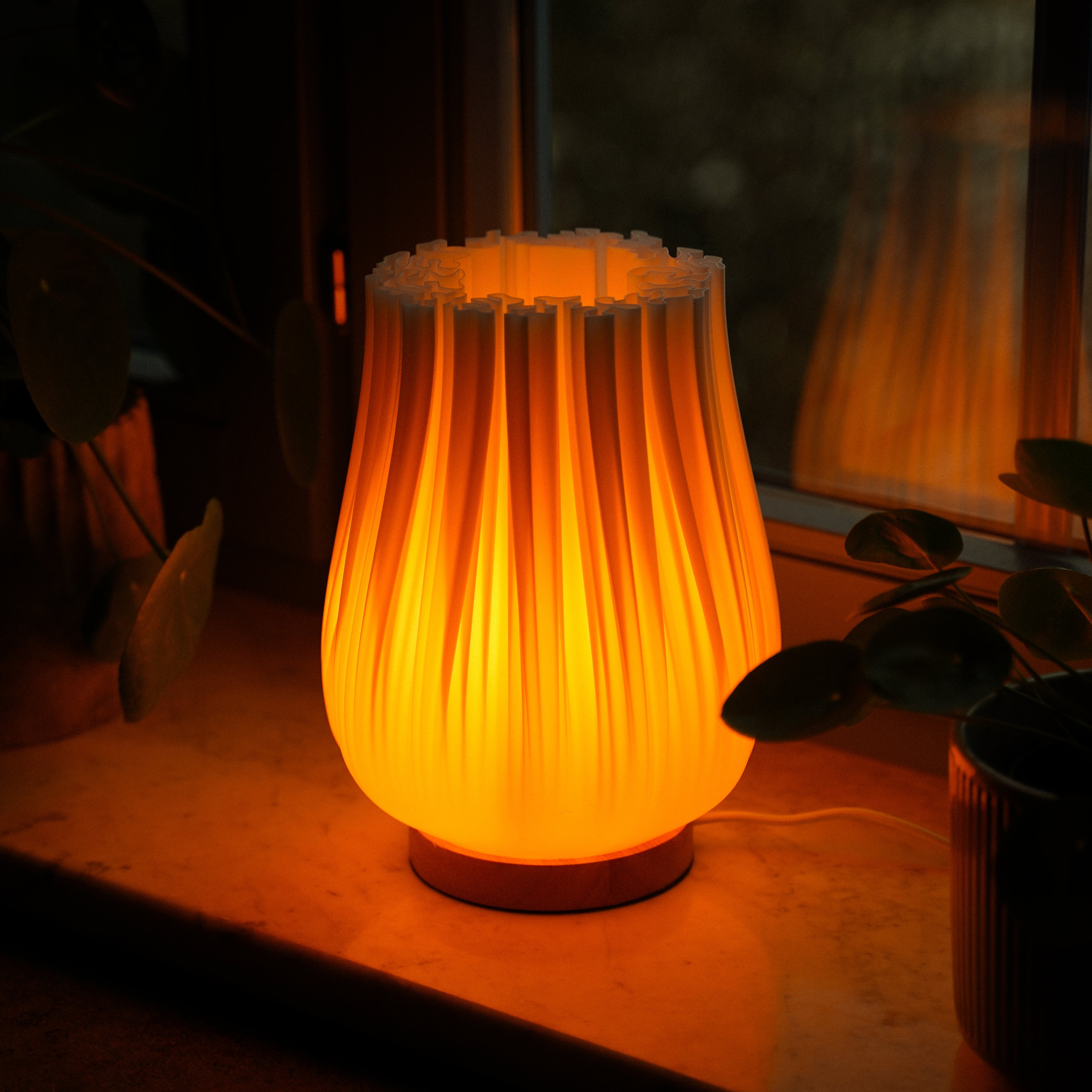 Moonou ‚Cora‘ – 3D-gedruckte Falten-Tischlampe mit warmweißem 2100 K Licht auf der Fensterbank; PLA-Schirm, Eichenholz-Sockel, E27, dimmbar