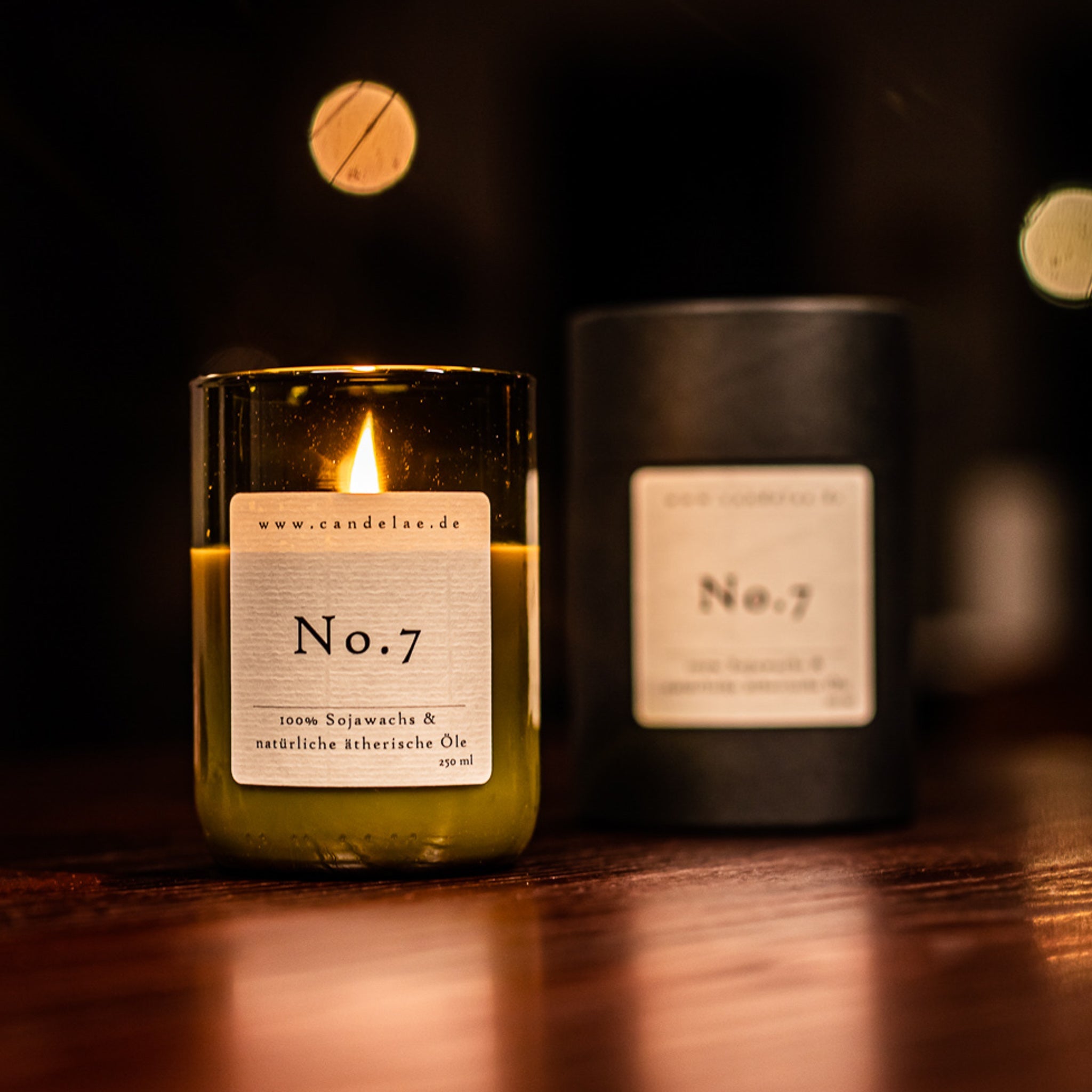 Duftkerze No.7 von Candelae – handgegossen aus Sojawachs mit ätherischen Ölen im Glas aus recycelter Weinflasche, brennend auf Holztisch.