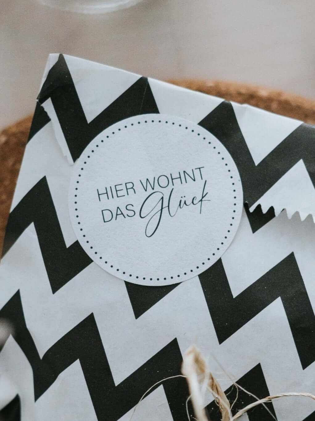 Weißer runder Aufkleber mit Schriftzug Hier wohnt das Glück, minimalistisches Design, 4 cm Durchmesser, CO₂-neutral produziert