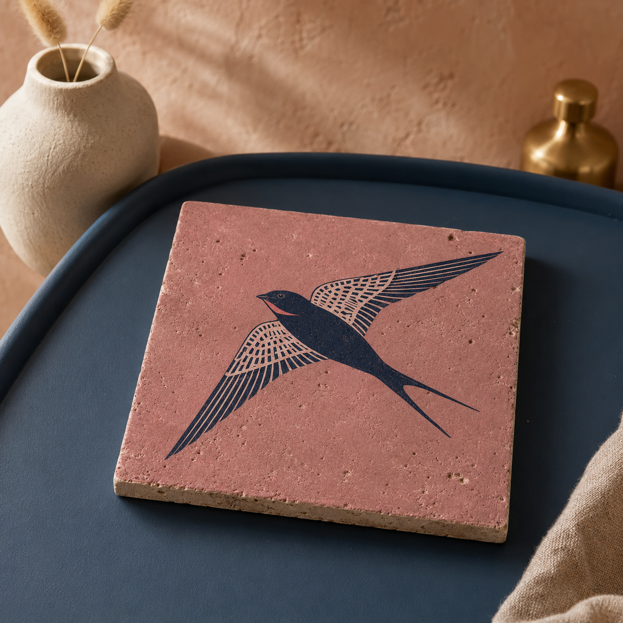 Travertin-Kunstwerk „Aufwind“ mit fliegender Schwalbe, liegend auf einem petrolblauen Tisch.