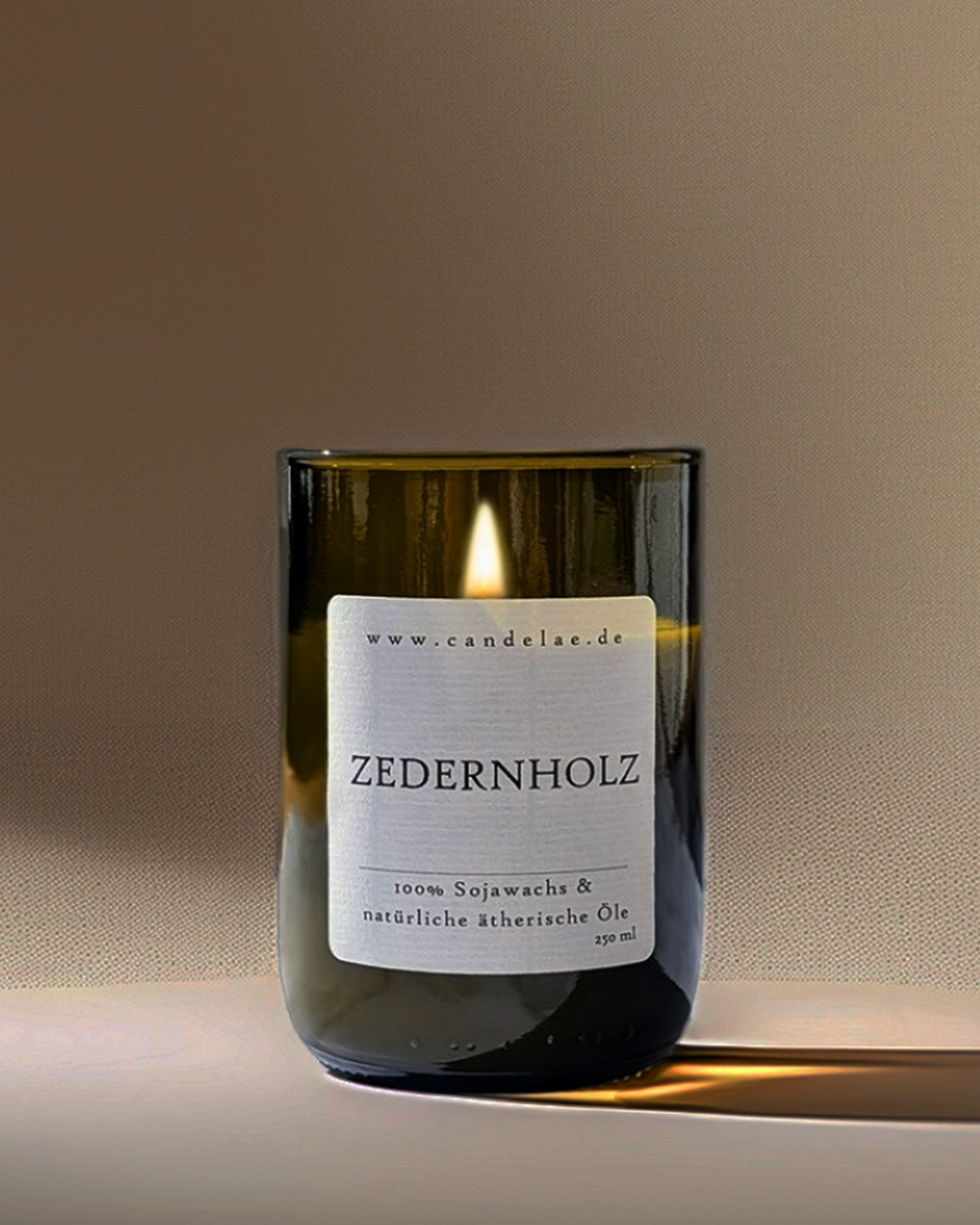 Candelae Duftkerze „Zedernholz“ – brennend, 250 ml Sojawachs im grünen Glas aus recycelter Weinflasche, mit natürlichen ätherischen Ölen; vegan, handgemacht.