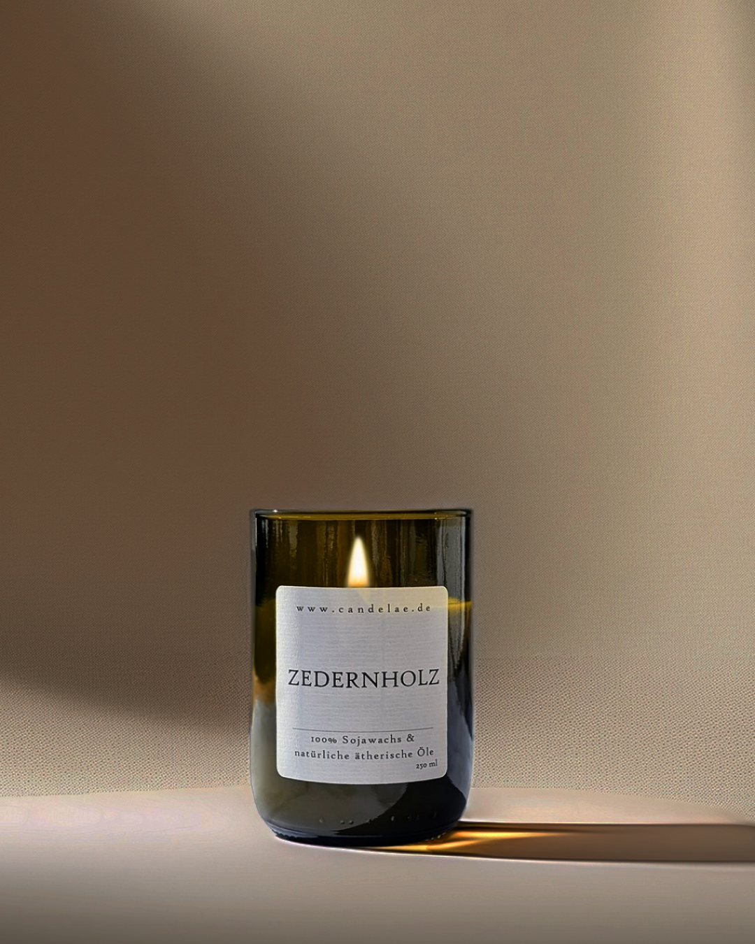 Candelae Duftkerze „Zedernholz“ – brennend, 250 ml Sojawachs im grünen Glas aus recycelter Weinflasche, mit natürlichen ätherischen Ölen; vegan, handgemacht.
