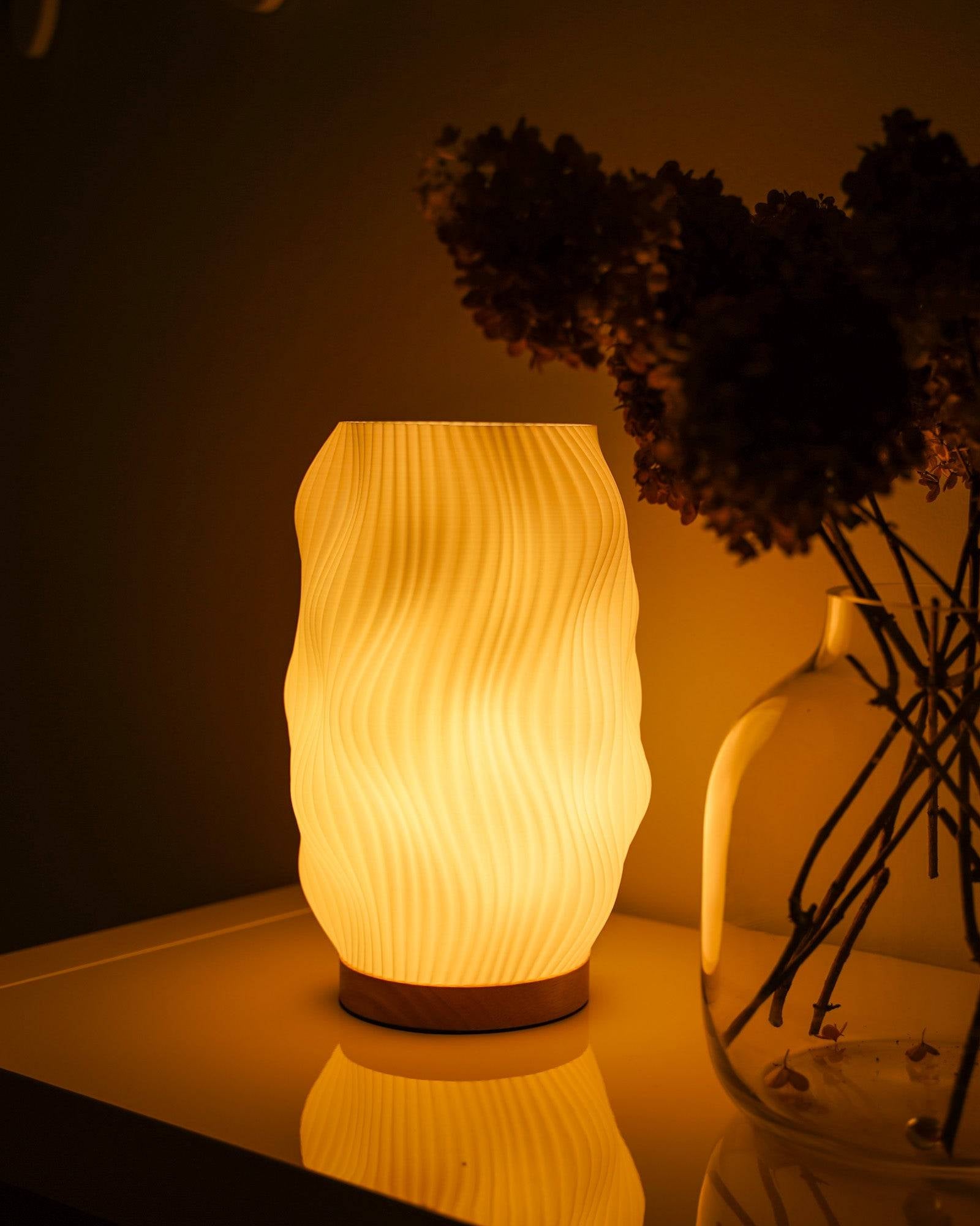 Moonou Flow 3D-gedruckte Tischlampe aus PLA mit Wellenstruktur und Eichenholz-Sockel, warmes Licht neben Glasvase